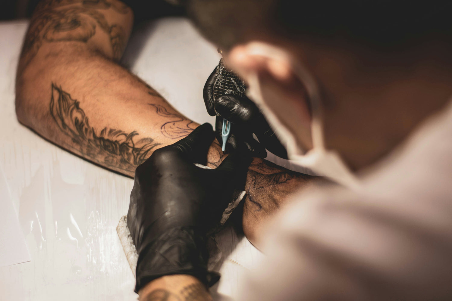 tattoo artist tattooing a forearm with tattoo ink